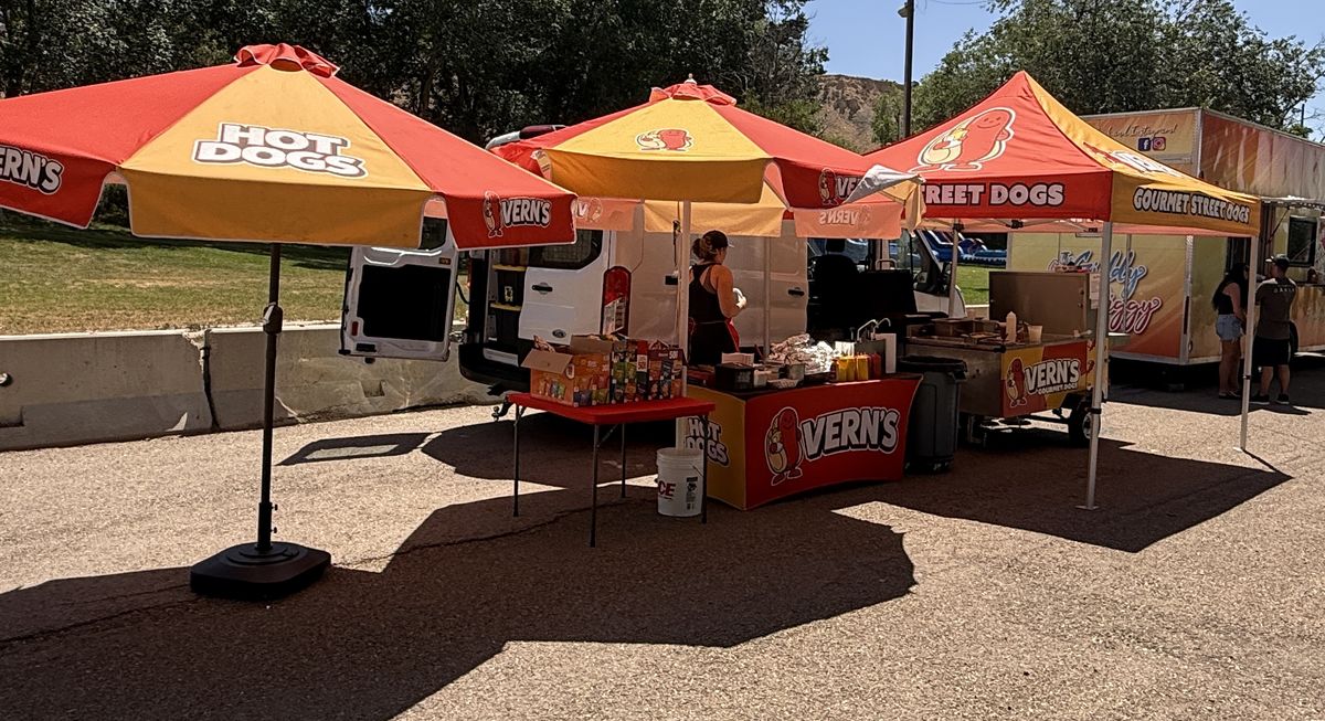 Branded Vern's umbrellas, canopy, cart, and table cover at an event